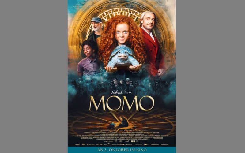 Filmplakat für "Momo" mit einem rotgelockten Mädchen, das eine Schildkröte in der Hand hält, umgeben von vier anderen Figuren, mit einem goldenen Zifferblatt im Hintergrund.