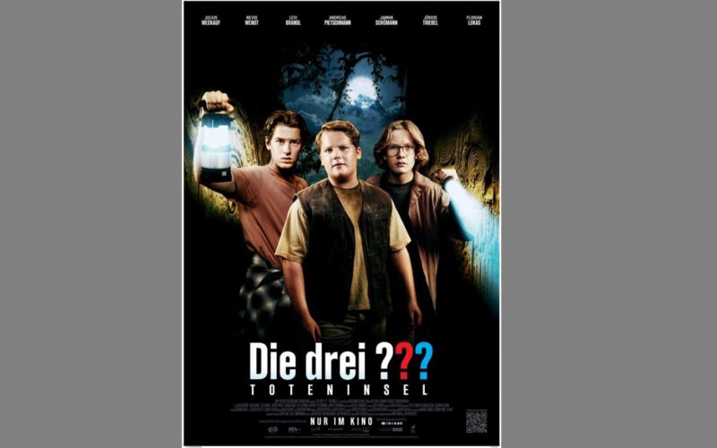 Drei Jungen stehen in einem dunklen Wald und halten Laternen und eine Taschenlampe in der Hand. Unter ihnen ist der Titel "Die drei ??? Toteninsel" steht auf einem Filmplakat unter ihnen.
