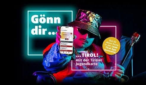 Ein Mann in glänzender Kleidung und mit Sonnenbrille hält ein Smartphone in die Höhe und wirbt in Neonschrift und -grafik für die Tiroler Jugendkarte.