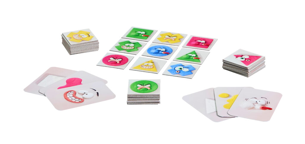 Auf einer weißen Fläche sind mehrere Stapel von Spielkarten mit bunten Cartoon-Gesichtern mit unterschiedlichen Ausdrücken angeordnet.