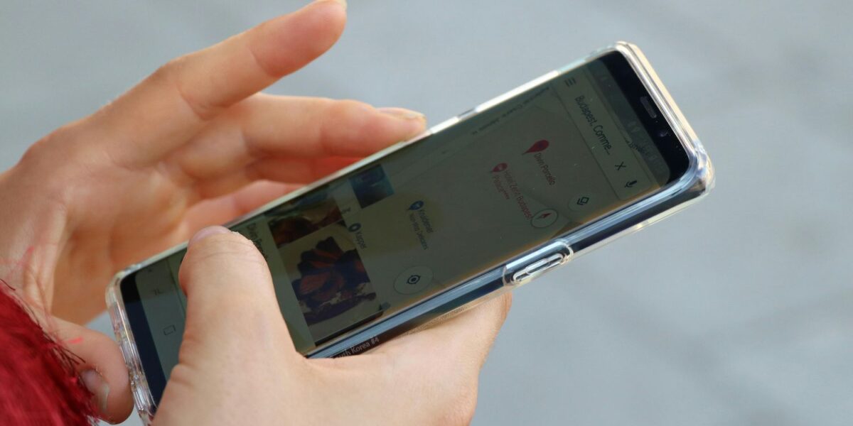 Eine Person hält ein Smartphone in der Hand, das eine Kartenanwendung anzeigt, auf deren Bildschirm Standortpins zu sehen sind.