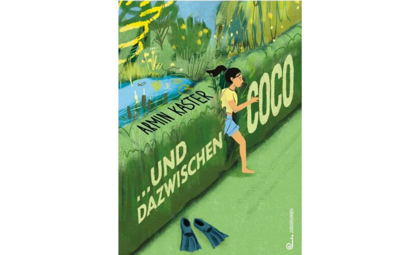 Ein Mädchen in Badekleidung geht neben einer hohen grünen Hecke mit der Aufschrift "Anni Kaster Und Dazwischen Coco" spazieren; Schwimmflossen liegen im Gras, und im Hintergrund ist ein Teich zu sehen.