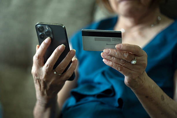Eine Person, die ein Smartphone in der einen und eine Kreditkarte in der anderen Hand hält, scheint eine Online-Transaktion durchzuführen.