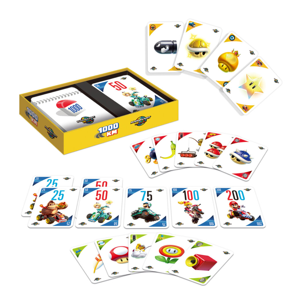 Eine Kartenspielschachtel mit der Aufschrift "1000 KM" mit Karten zum Thema Mario Kart, auf denen Figuren, Fahrzeuge, Gegenstände und Zahlen auf einem weißen Hintergrund abgebildet sind.