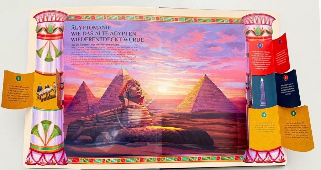 Aufgeschlagene Seite eines Aufklappbuchs mit einer zentralen Illustration der Großen Sphinx und der Pyramiden bei Sonnenuntergang, umgeben von deutschem Text und Seitenrändern.